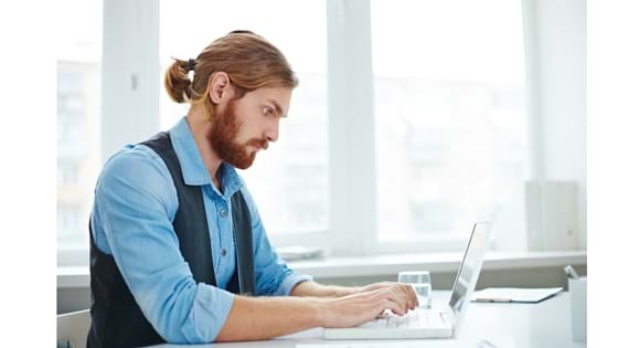 Man Typing a cover letter on a laptop