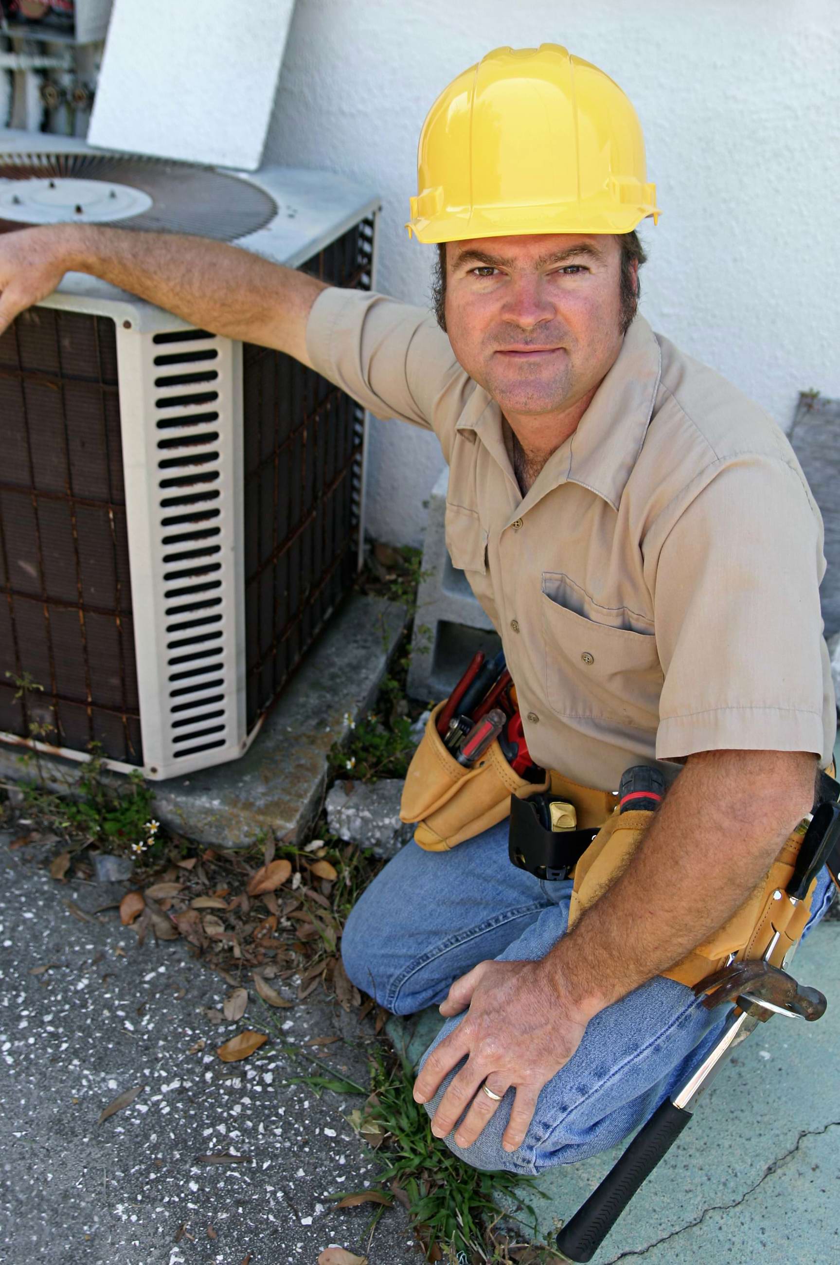 Man kneeling next to an AC unit